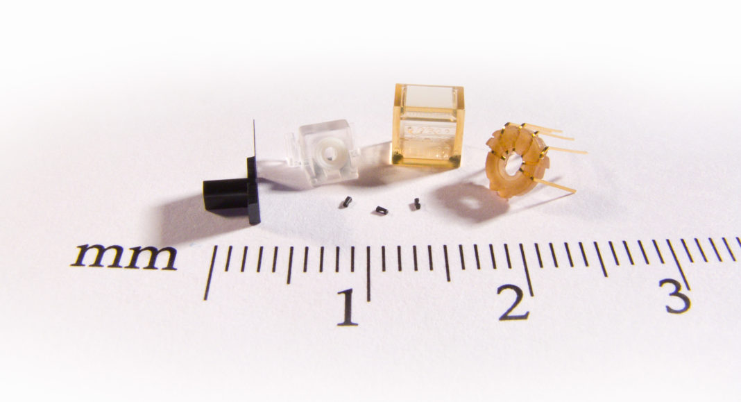 Examples pushing the limits with micro injection molding: From the left: (LCP) 76 µm thin-wall, (ABS & TPU) 2-shot with 2 mm soft diameter center ring, (PEI/Ultem) micro features with 250 µm diameter lenses, (PEEK) lead frame insert molding. In the center: (LCP-mineral filled) 800 µm longest feature.